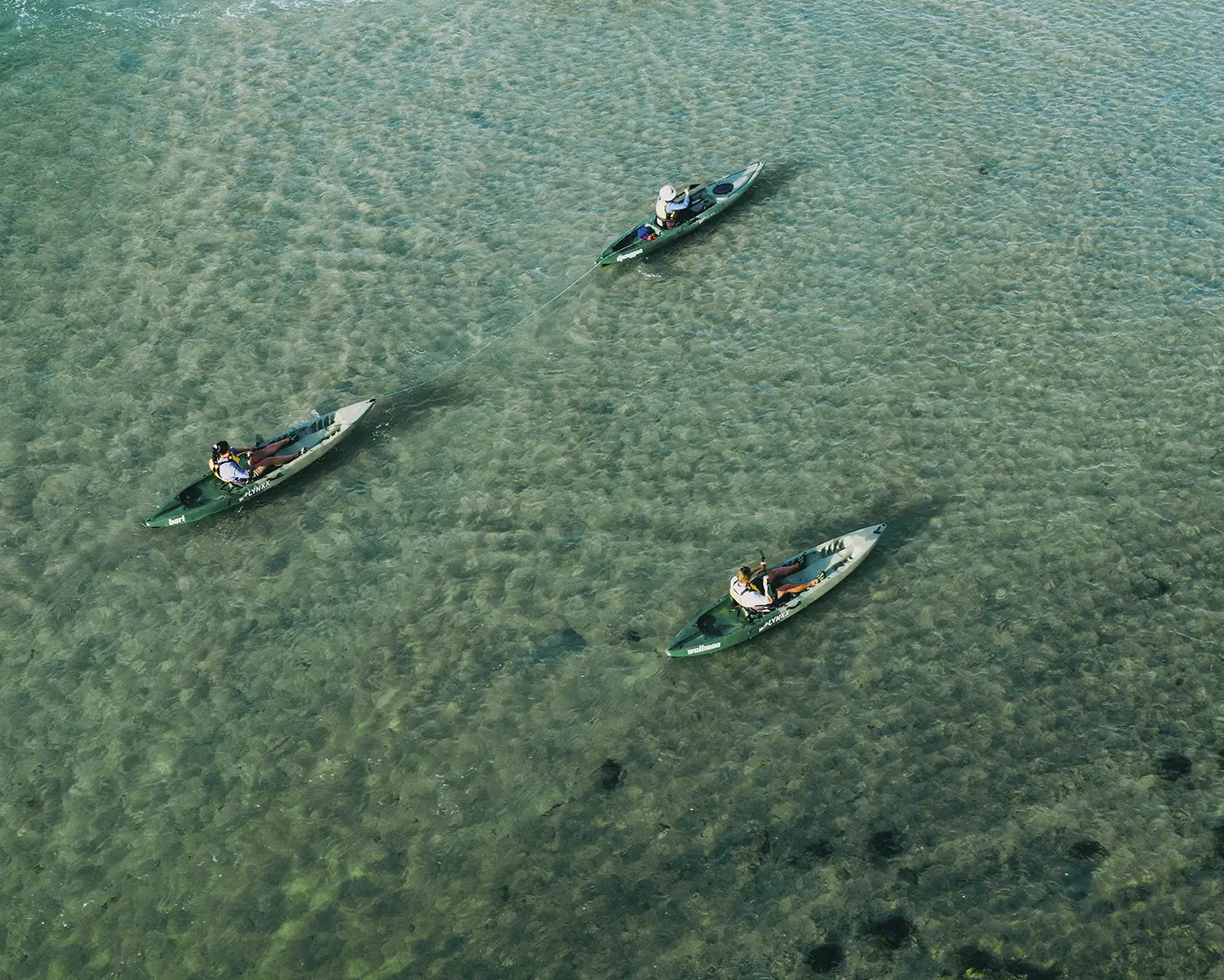 Aerial drone photography of three people in kayaks on the calm Pambula River.